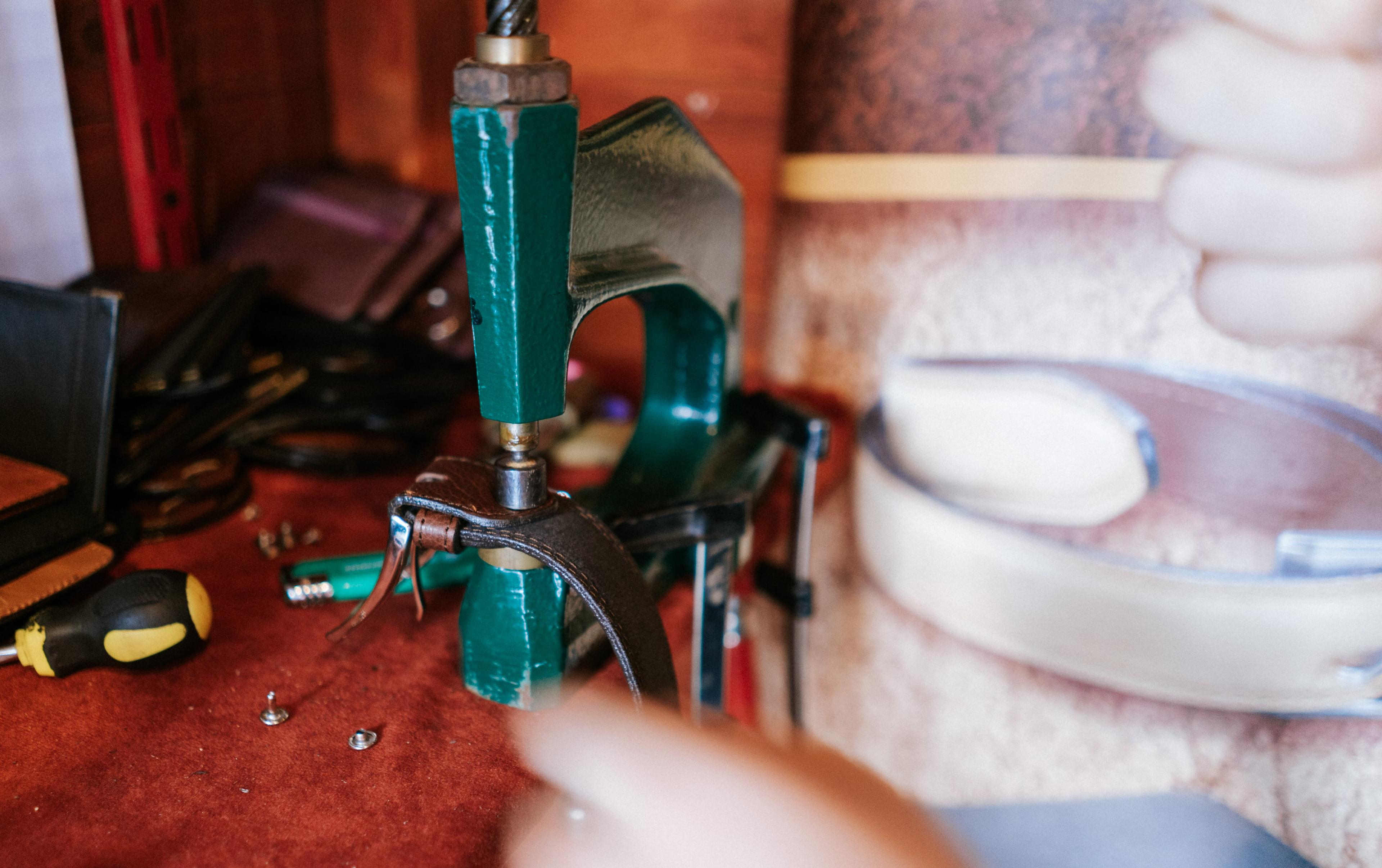 artisan pressing holes into belt