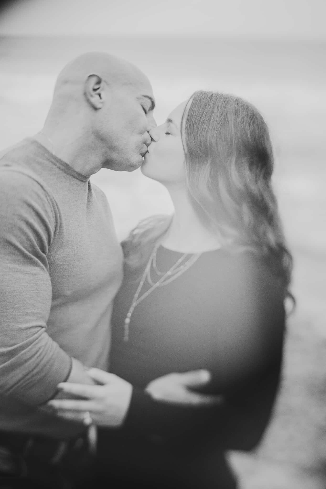 A creative black and white soft portrait of a couple kissing during their engagement session at Montauk lighthouse in Long Island New York