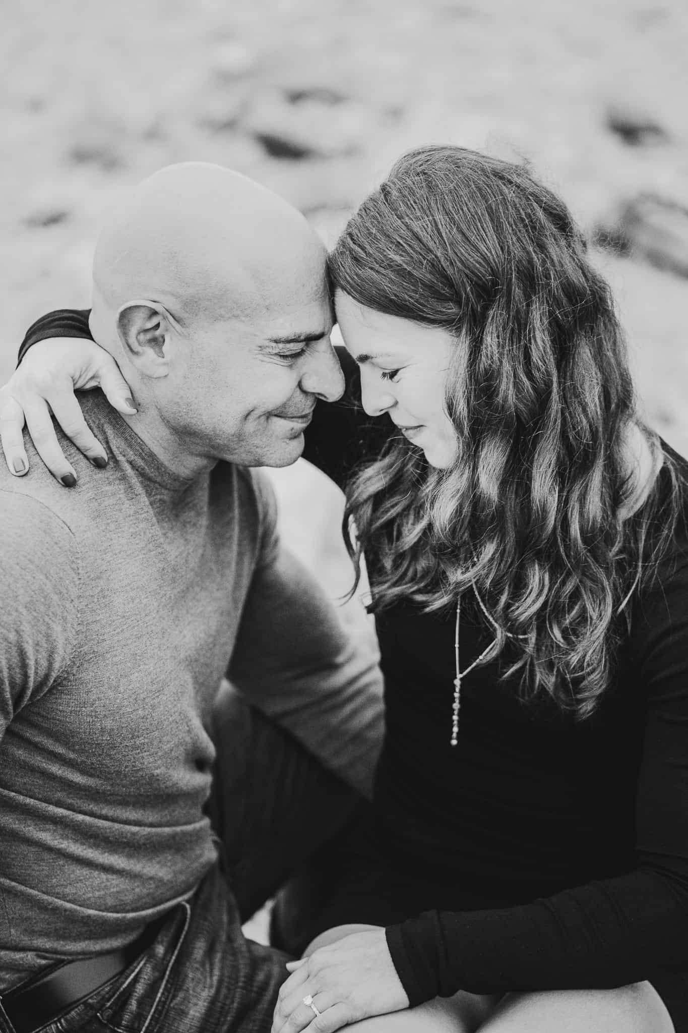 Black and white photo of a couple resting their heads together and smiling during their engagement session at Montauk lighthouse in Long Island New York