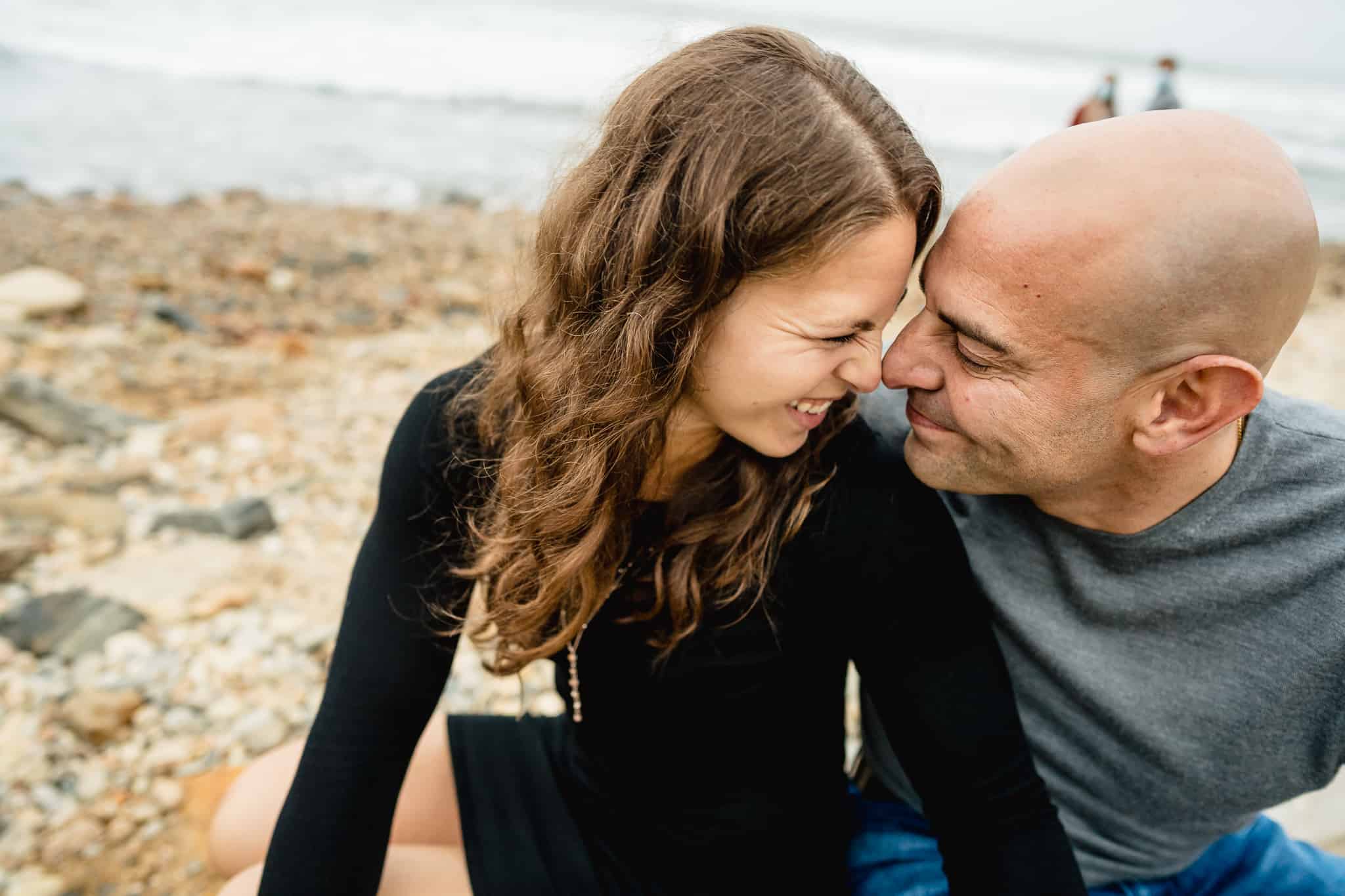 A couple giving each other an Eskimo kiss during their engagement session on the beach at Montauk lighthouse in Long Island New York