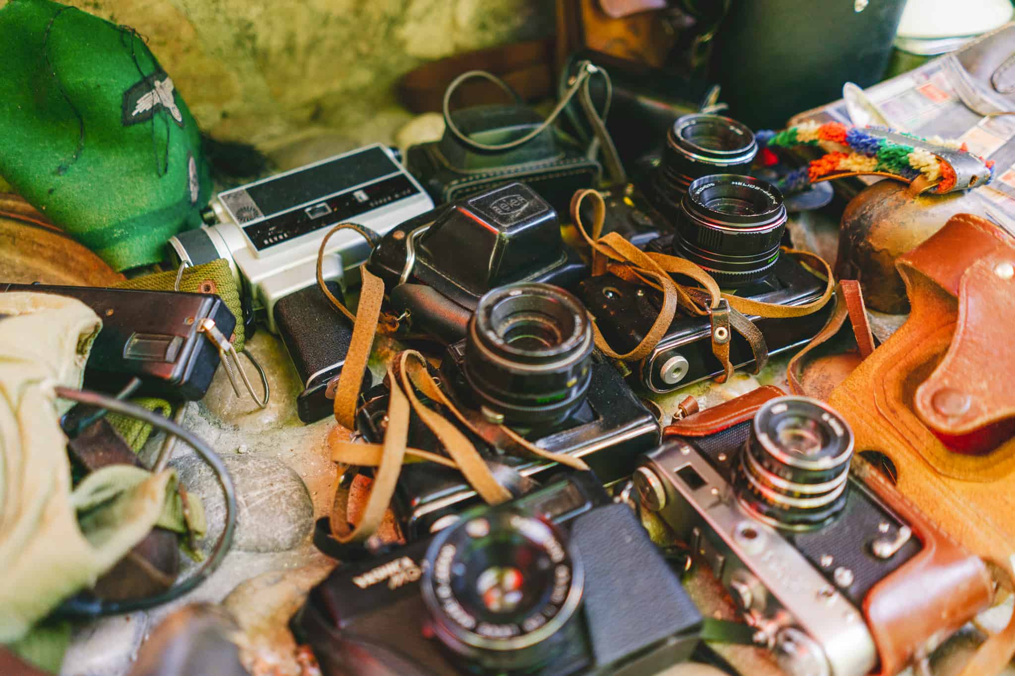 A saturated photo of old vintage cameras lying on stones