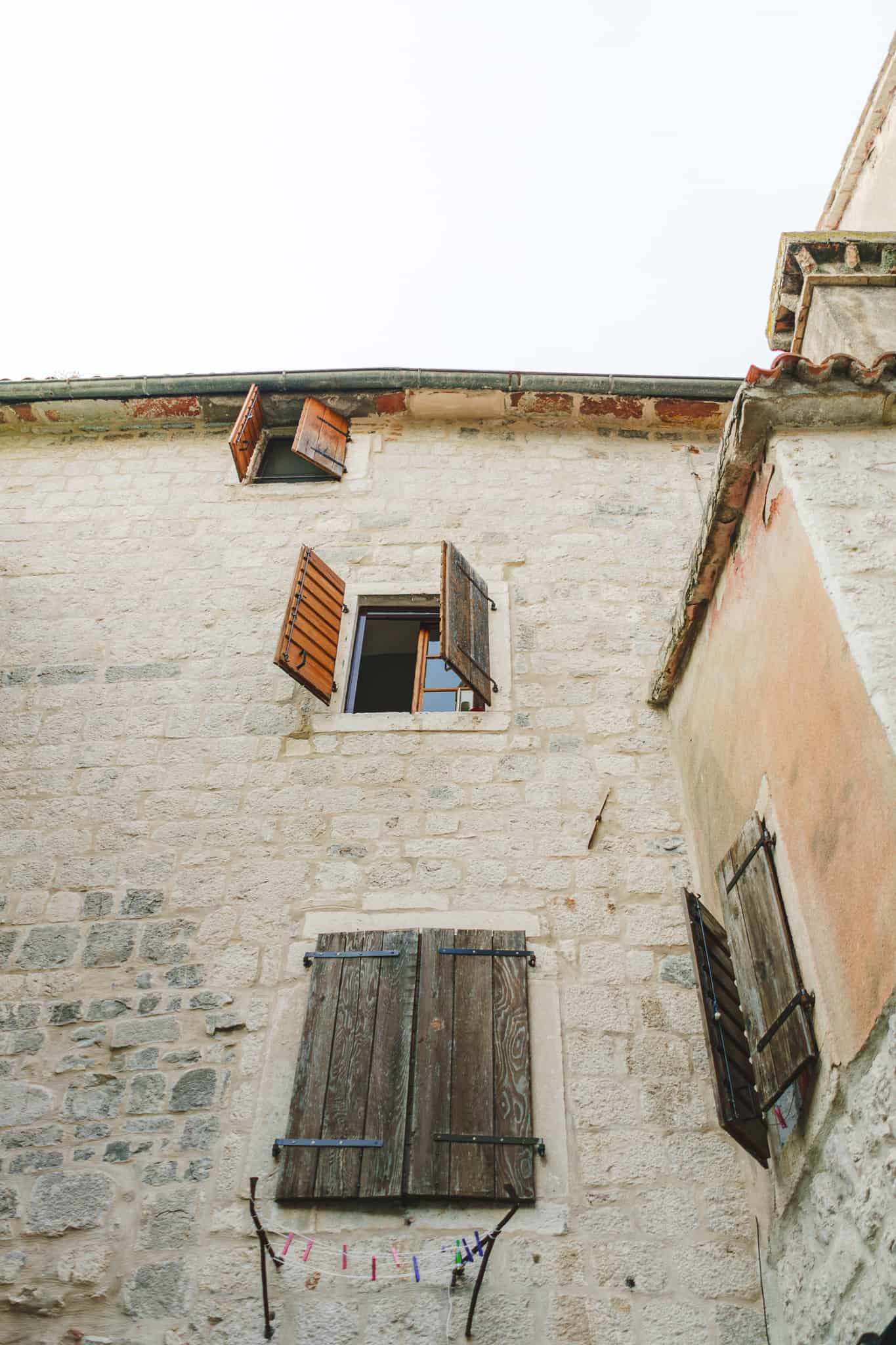 Three wooden windows on a white brick Mediterranean wall of a house in Kotor Montenegro