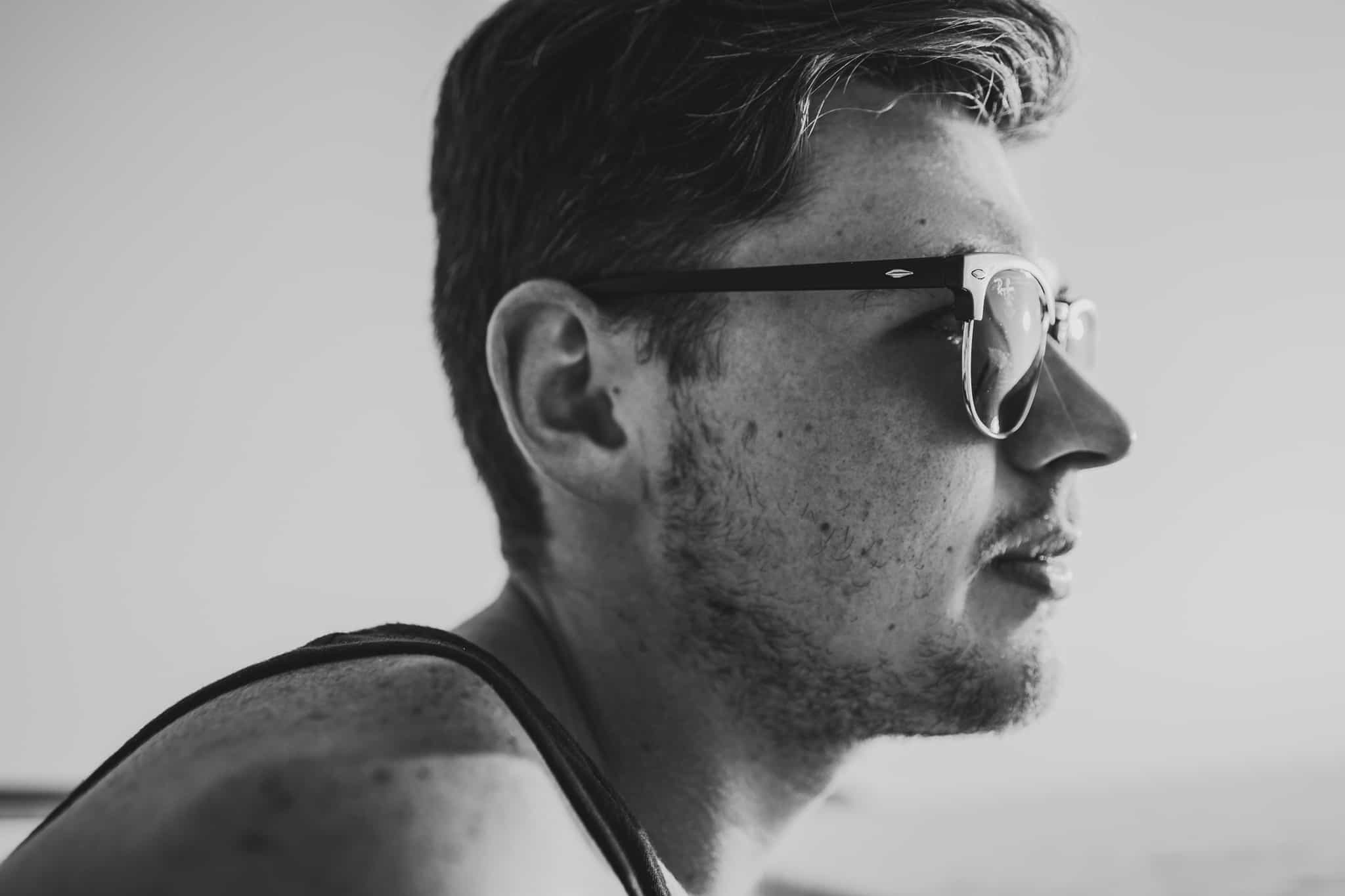 Black and white headshot side profile of Tristan Wallace wearing ray-bans while in Montenegro