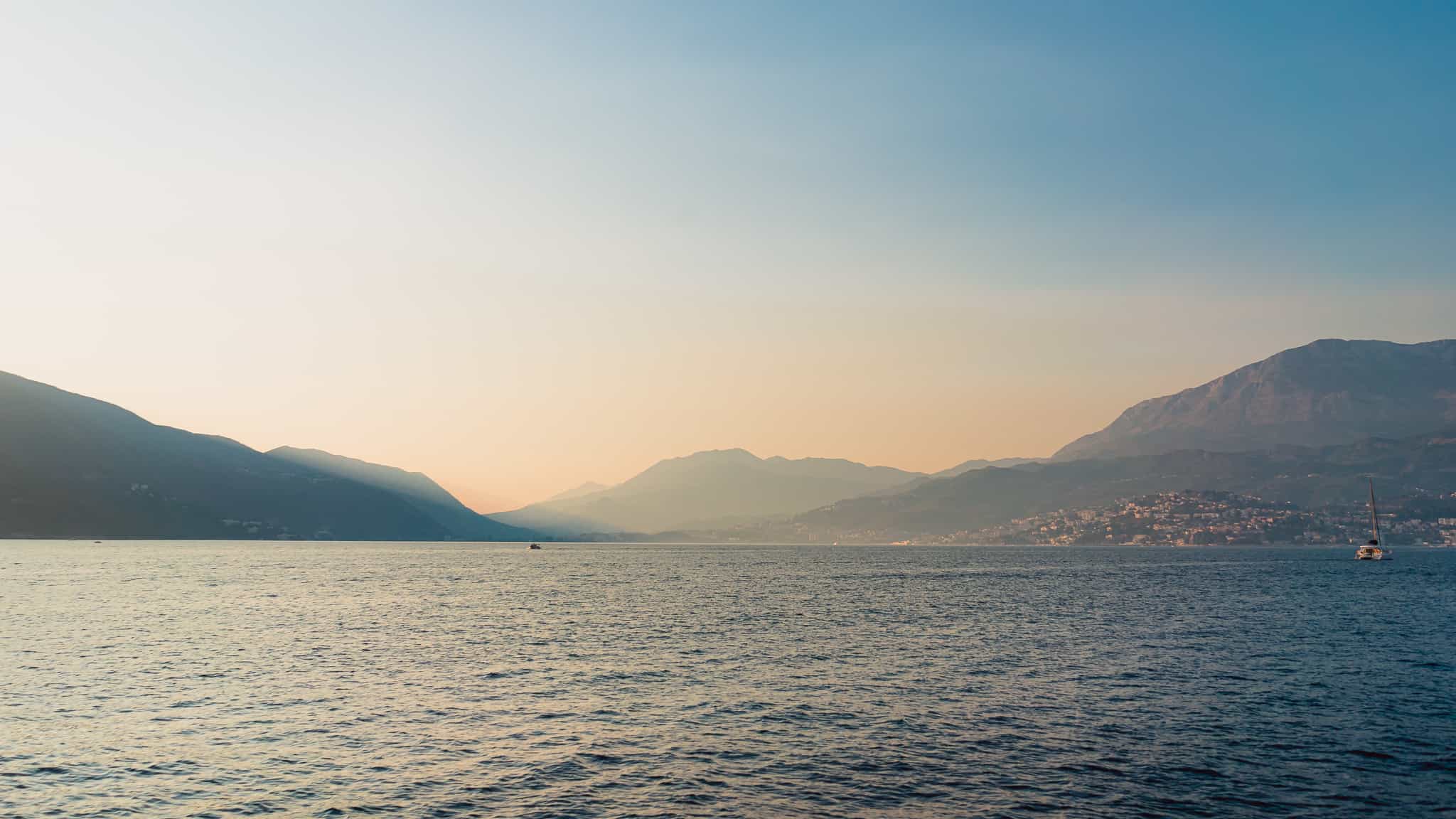 A gorgeous soft sunset photo of the water and hills of Kotor Montenegro