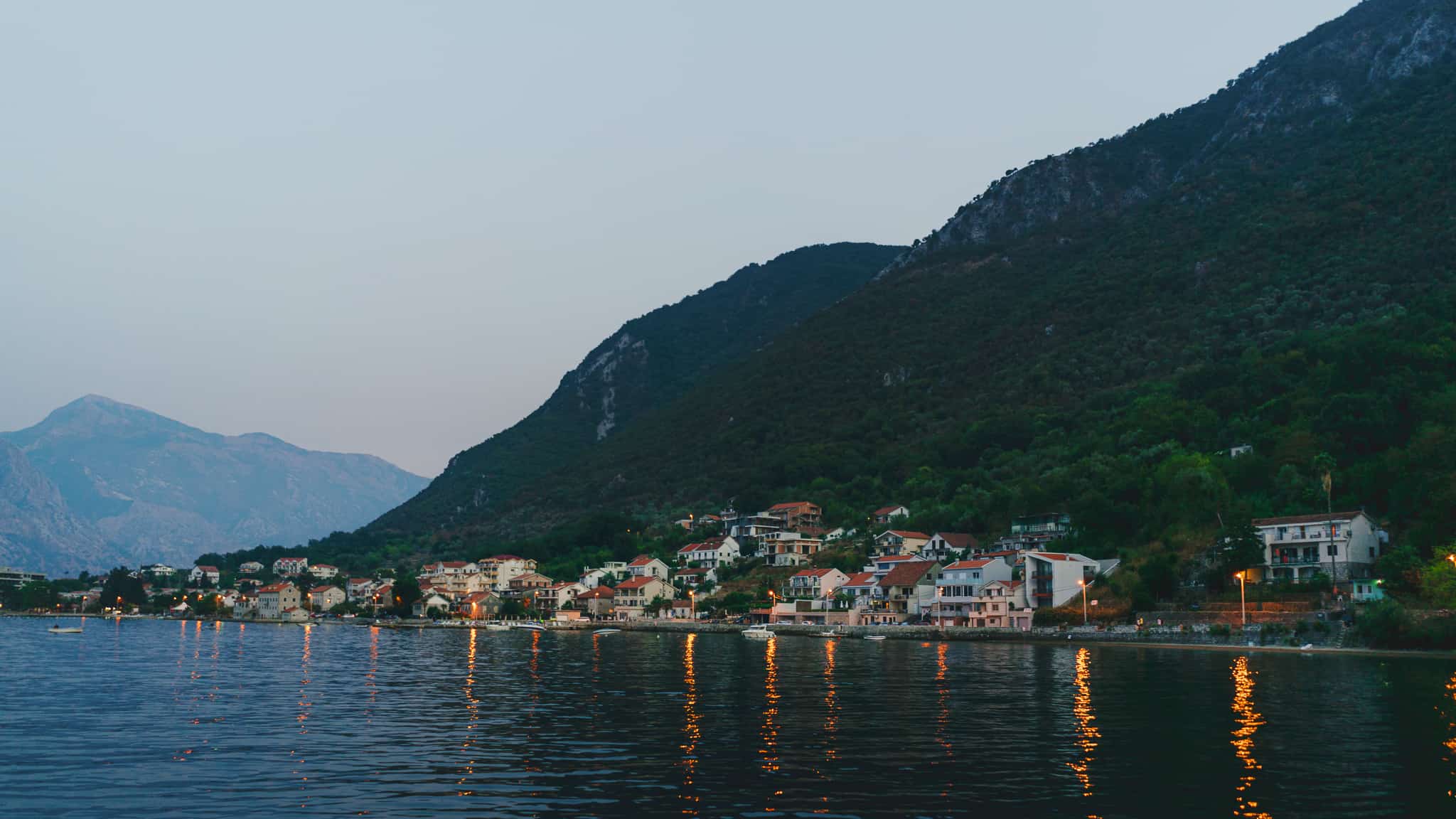 Buildings on the hillside of the bay of  Kotor in Montenegro shot at blue hour with their warm street lights glistening in the water
