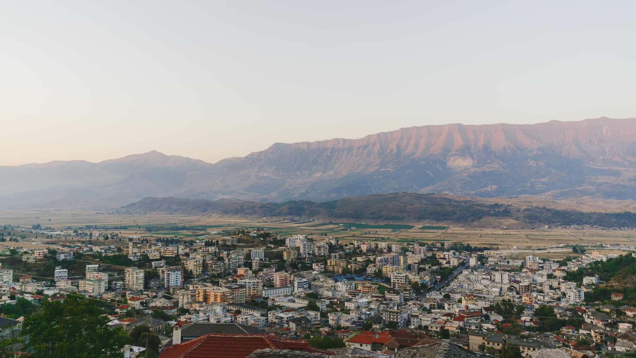 Wide epic landscape of gjirokaster Albania at sunset with soft light bathing over buildings