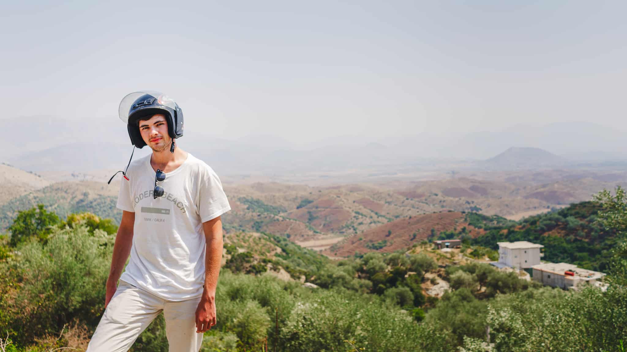 Tristen Wallace with a scooter helmet and sunglasses on in the hills of Albania