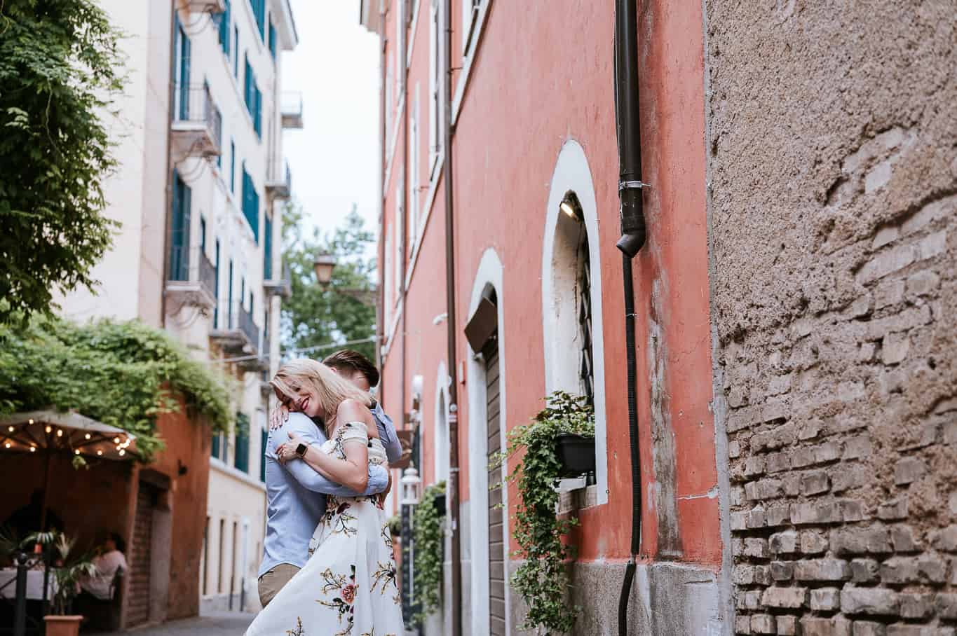 Coupled dancing and hugging in front of brightly covered buildings amongst the streets of trust every in Rome Italy