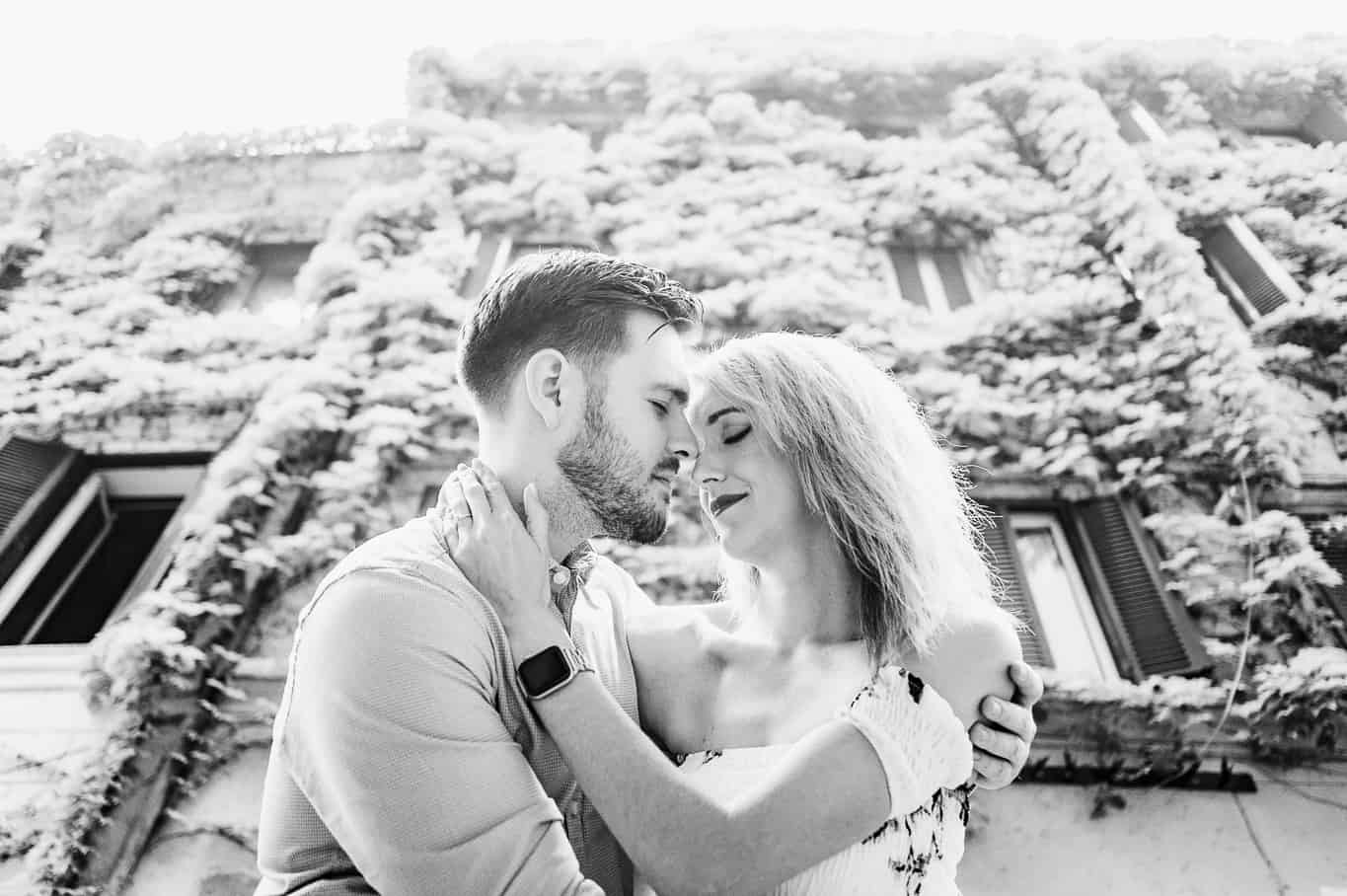 Black and white photo of couple during engagement photo shoot in front of building covered in Ivy on the streets of trastevere a in Rome Italy