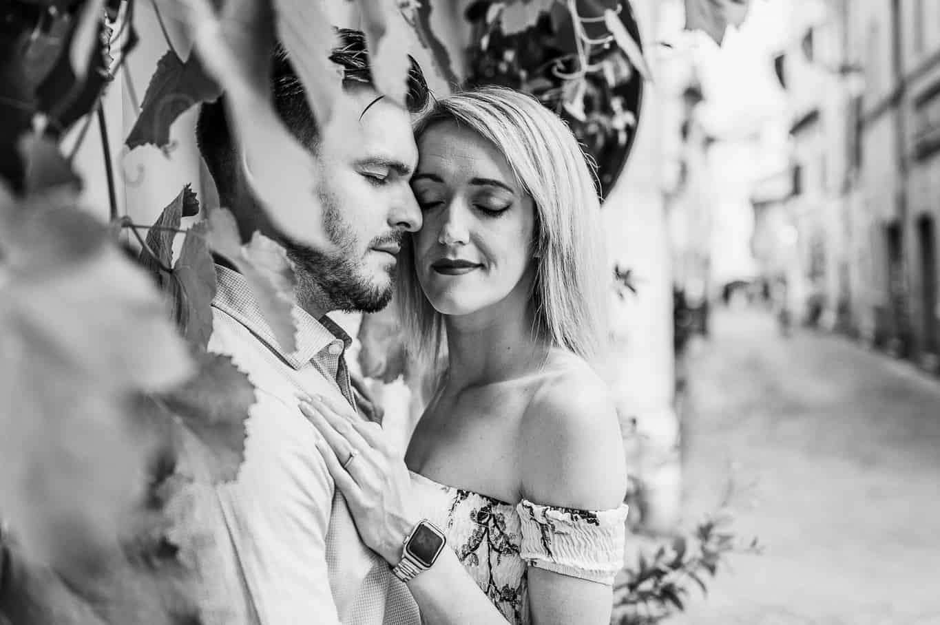 Black and white photo of couple snuggling with eyes closed during engagement photo shoot in front of Ivy covered walls on the streets of trastevere in Rome Italy